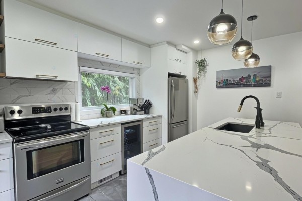 Modern kitchen with white cabinetry, stainless steel appliances, and a large island. - 40 Ch. Cochrane, Gatineau