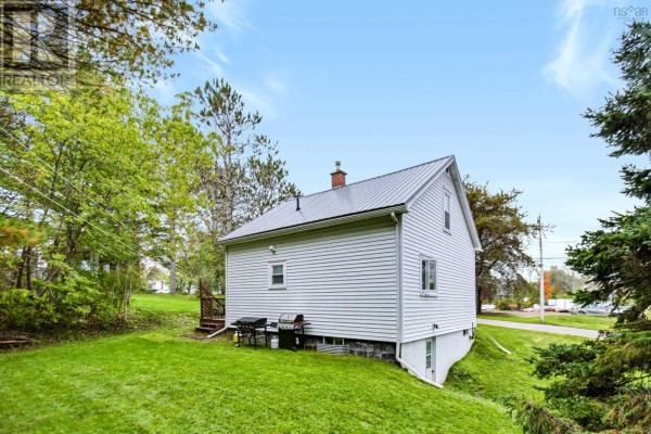 Side view of white house with metal roof, surrounded by green lawn and trees. - 40 Charles Street, Amherst