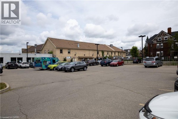 Wide exterior shot of the apartment building and parking lot under a cloudy sky. - 40 East Avenue, Brantford