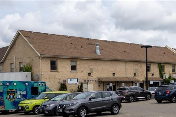 Close-up view of the brick apartment building exterior with parked cars in front. - 40 East Avenue, Brantford