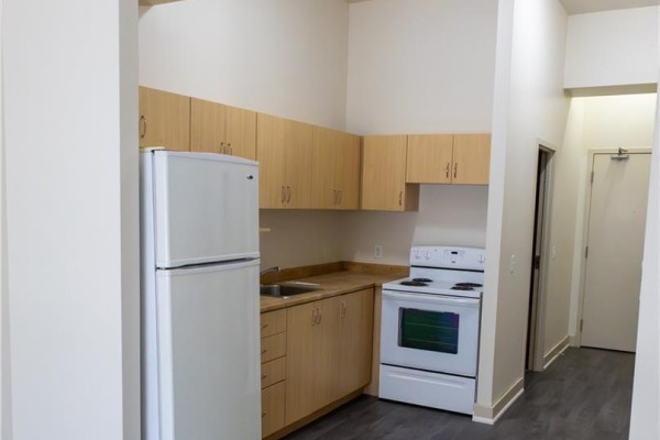 Compact kitchen area with light wood cabinets, white refrigerator, and white stove. - 40 East Avenue, Brantford