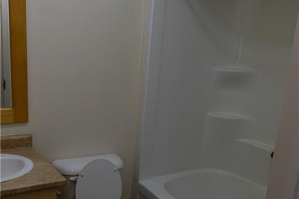 Small bathroom featuring a white bathtub, toilet, and vanity with a beige countertop. - 40 East Avenue, Brantford