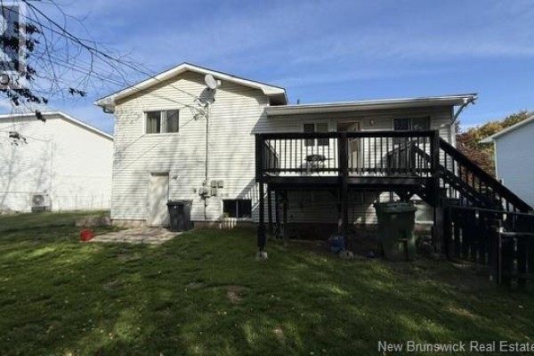 Rear exterior of a white house with a dark wooden deck and stairs, overlooking a grassy yard. - 40 Emmerson Street, Fredericton