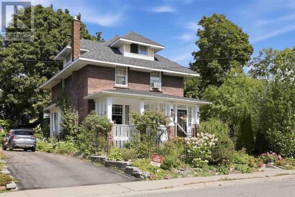 Side exterior view of a two-story brick house with a driveway and mature trees. - 40 Euclid Rd, Sault Ste  Marie