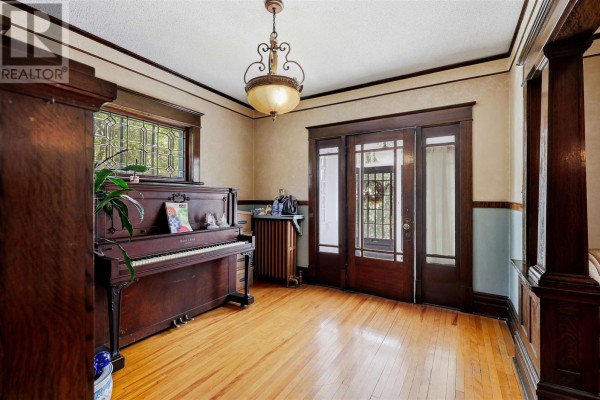 Living room with a dark wood upright piano, hardwood floors, and double glass doors. - 40 Euclid Rd, Sault Ste  Marie