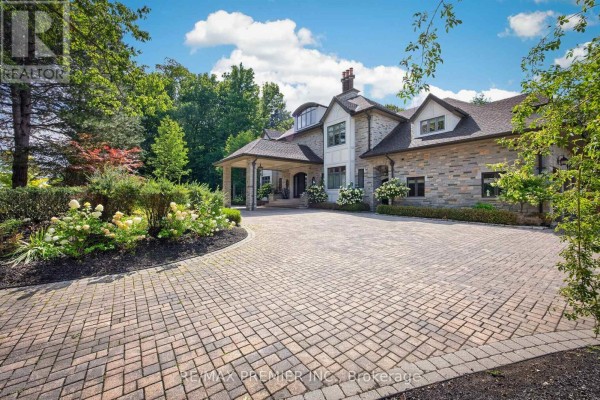 Stone residence with a circular driveway, manicured hedges, and mature trees. - 40 Golf Avenue, Vaughan
