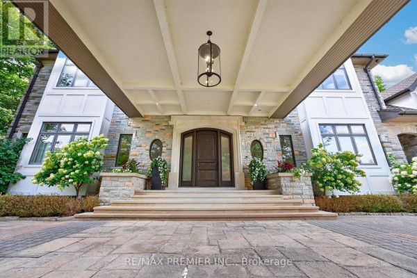 Entrance to a large stone home with a covered portico, grand staircase, and double wooden doors. - 40 Golf Avenue, Vaughan