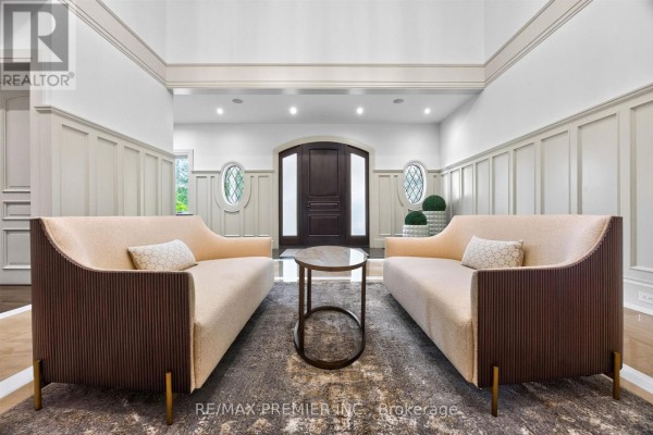 Foyer with two cream-colored sofas, a circular coffee table, and decorative oval windows. - 40 Golf Avenue, Vaughan