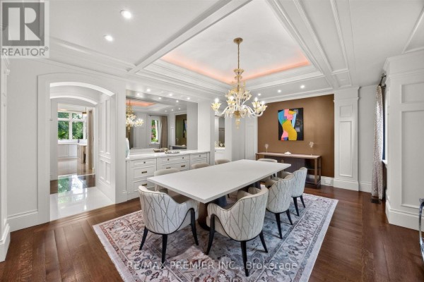 Dining room with a long white table, upholstered chairs, a crystal chandelier, and a buffet. - 40 Golf Avenue, Vaughan