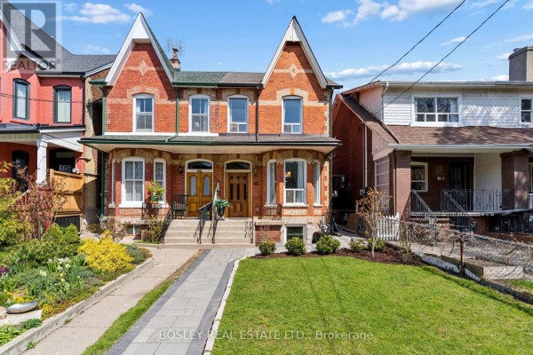 Front exterior of a red brick home with manicured lawn and stone walkway. - 40 Halton Street, Toronto