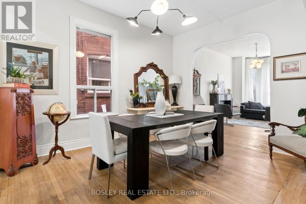Living room with hardwood floors, fireplace, antique secretary desk, and modern seating. - 40 Halton Street, Toronto