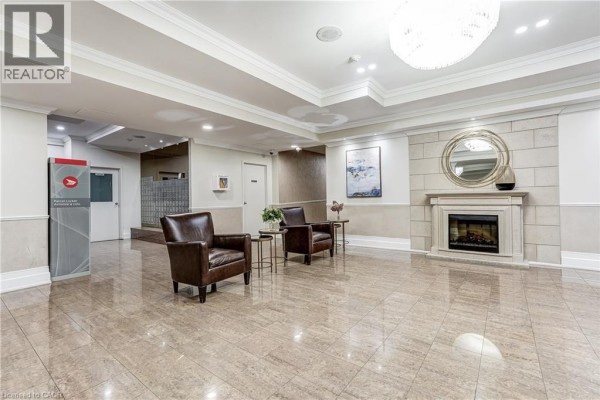 Building lobby featuring a decorative fireplace, leather armchairs, and a large circular mirror above the mantelpiece. - 40 Harding Boulevard Unit# 603, York