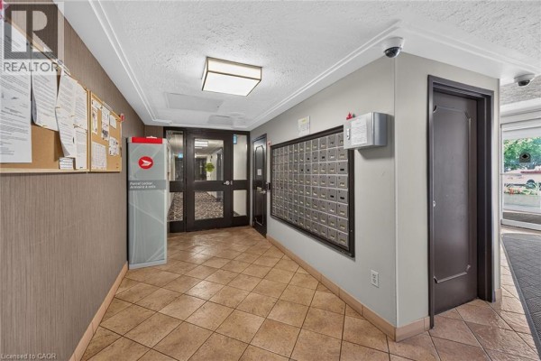 Hallway with mailboxes, parcel locker, corkboard, and elevators visible. - 40 Harrisford Street Unit# 103, Hamilton