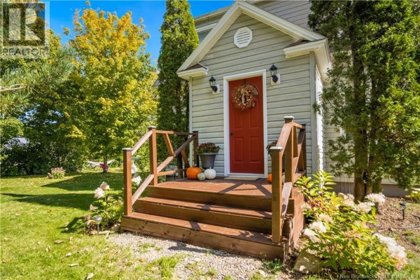 Close-up of a red front door with a wreath and pumpkins on a wooden porch with wooden railings. - 40 Mill Road, Elgin