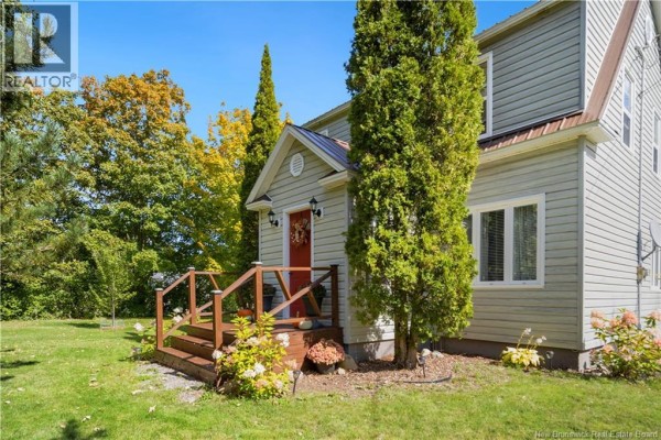 Front porch of a light green house with a red door and wooden railings surrounded by trees and grass. - 40 Mill Road, Elgin
