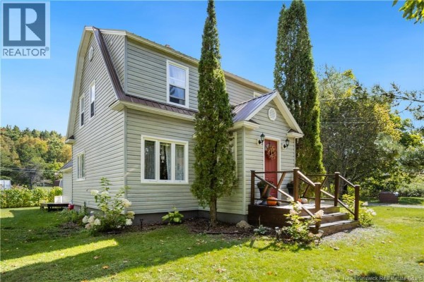 A two-story light green house with a gambrel roof and a red front door, surrounded by mature trees and a lawn. - 40 Mill Road, Elgin
