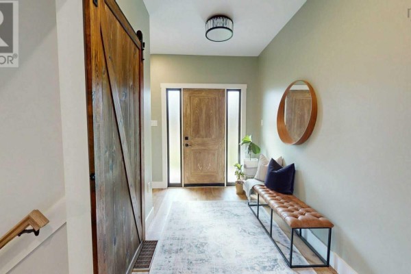 Entrance hallway with light green walls, a wooden barn door, and a long leather bench. - 40 Naveen Lane, Antigonish