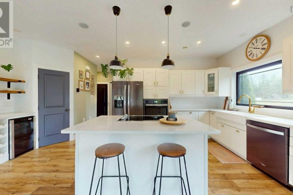 Modern white kitchen with a large island, stainless steel appliances, and wooden floors. - 40 Naveen Lane, Antigonish
