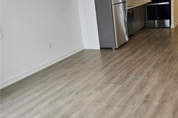 View of the light wood-look flooring extending into the kitchen area with stainless steel appliances. - 40 Palace Street Unit# J2, Kitchener