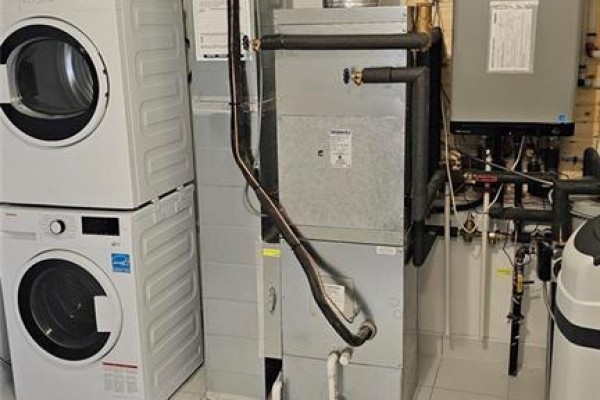 Utility area with stacked white washer and dryer, a furnace, and a water heater. - 40 Palace Street Unit# J2, Kitchener