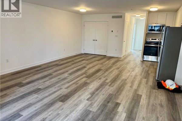 View of the open living area and kitchen from the opposite side, showing double doors. - 40 Palace Street Unit# L24, Kitchener