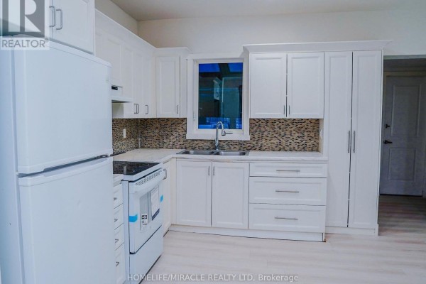 White kitchen with white cabinets, mosaic tile backsplash, sink, and window. - 40 Parkhill Road, Cambridge