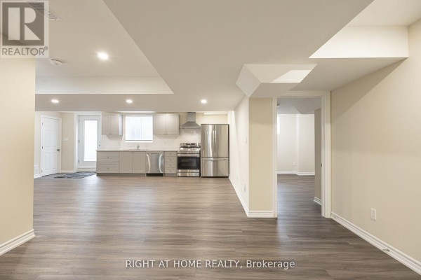 Open-concept basement with a grey kitchen, stainless steel appliances, and laminate flooring. - Basement - 40 Sabbe Crescent, Ajax
