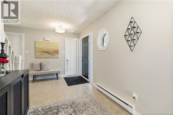 View of an entryway with a black door, bench, artwork, and a view of the staircase. - 40 Tamarack Terrace, Moncton