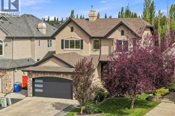Front exterior of a two-story home with stone accents and mature trees. - 40 Tuscany Glen Park Nw, Calgary