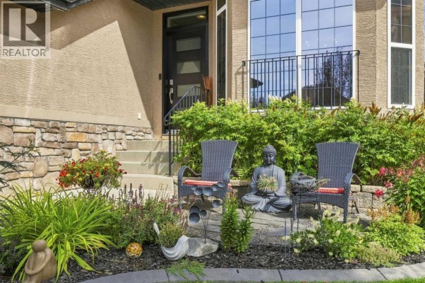 Front entrance detail with stone and stucco, featuring two chairs and garden. - 40 Tuscany Glen Park Nw, Calgary