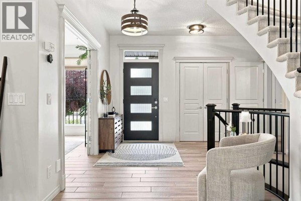 Interior view of a bright entryway with a staircase and double doors. - 40 Tuscany Glen Park Nw, Calgary