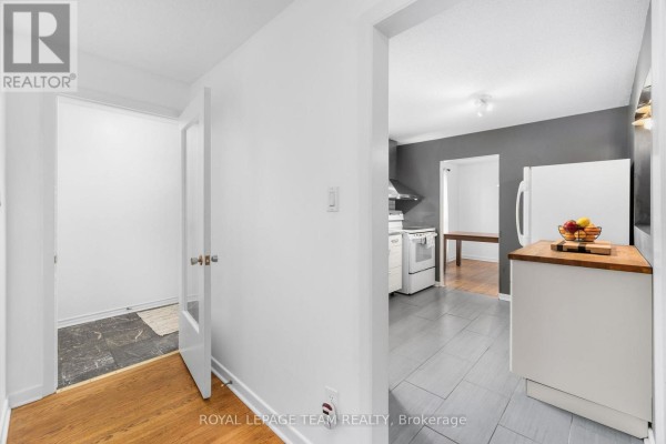 Interior hallway with wood flooring leading to a doorway revealing a kitchen. - 40 Woodmount Crescent, Ottawa