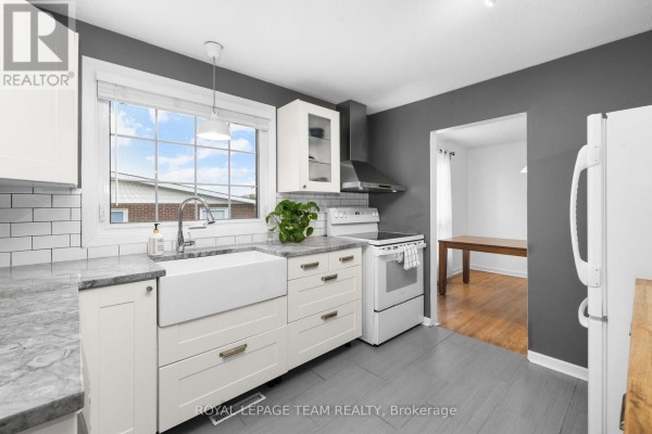White kitchen with grey walls, a farmhouse sink, white cabinets, and a stainless steel range. - 40 Woodmount Crescent, Ottawa
