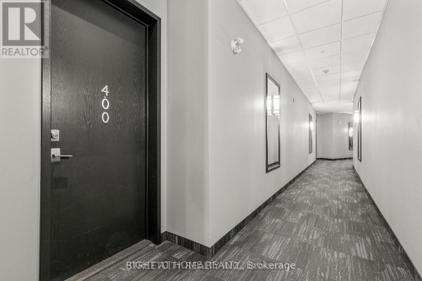 Hallway on an apartment floor with a dark wood door labeled 400 and patterned carpet. - 400 - 1705 Fiddlehead Place, London North