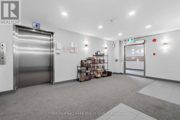 Apartment building lobby with stainless steel elevator doors, carpeted floor, and a bookshelf. - 400 - 218 Viewmount Drive, Ottawa