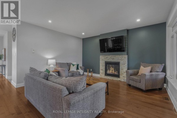 Open-concept kitchen with island, dining area, and living room with stone fireplace. - 400 Colmar Street, Russell