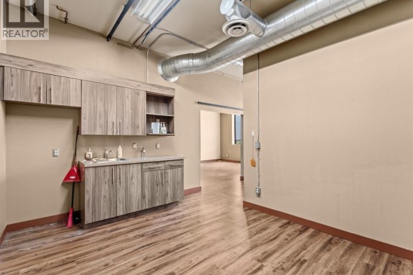 Large room with wood-plank flooring, built-in shelving, and exposed ventilation ducts. - 400 Erie Street East Unit# 1 & 2, Windsor