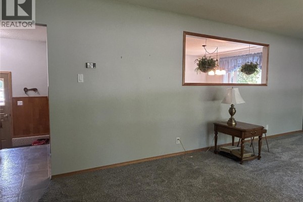 View into dining area through a large square opening in the wall. - 400 Gallaway Street, Estevan