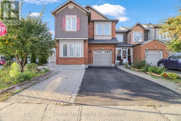 Front exterior view of a red brick townhouse with multiple windows and an attached garage. - 400 Meadowhawk Crescent, Ottawa