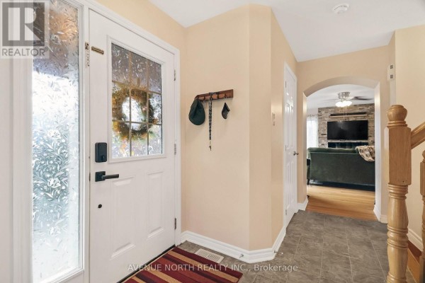 Interior entryway with a white front door, grey tiled floor, and a coat rack on a pale peach wall. - 400 Meadowhawk Crescent, Ottawa