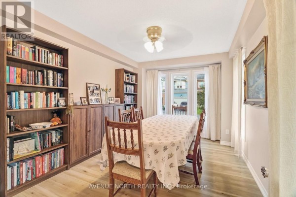 Dining room with a table set for a meal, two wooden bookcases, and light wood flooring. - 400 Meadowhawk Crescent, Ottawa