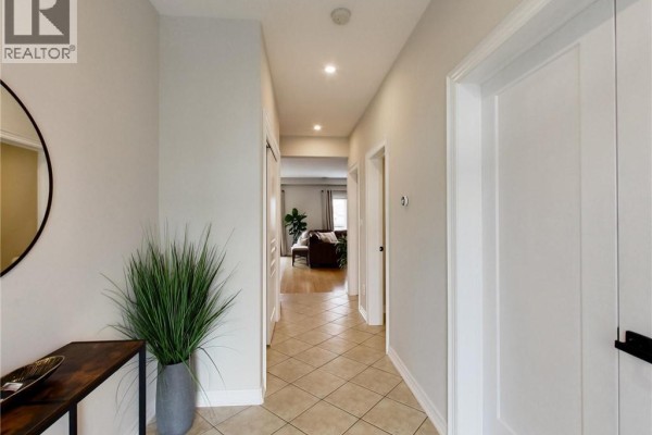 Interior hallway with beige tiled floors, light grey walls, and a large mirror. - 4007 Bush Crescent, Beamsville