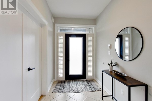 View of the front entrance with a frosted glass door, patterned rug, and a round mirror. - 4007 Bush Crescent, Lincoln
