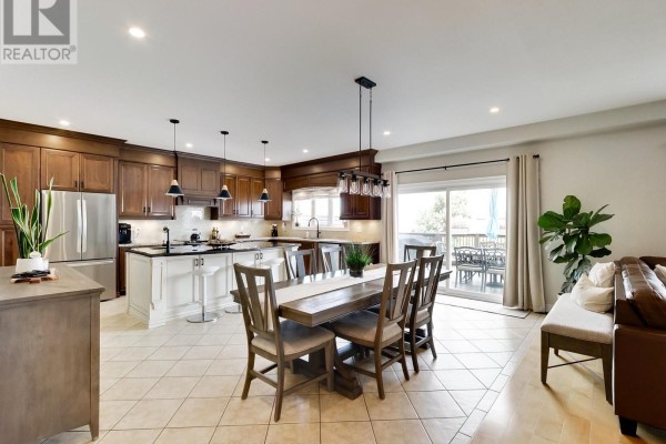 Open-concept kitchen and dining area with dark wood cabinets, an island, and sliding doors to a deck. - 4007 Bush Crescent, Lincoln