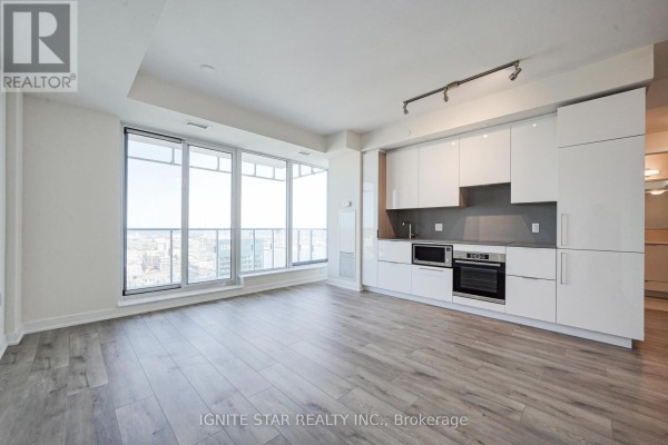 Open-concept living area with large windows, white cabinetry, and stainless steel appliances - 4008 - 28 Freeland Street, Toronto