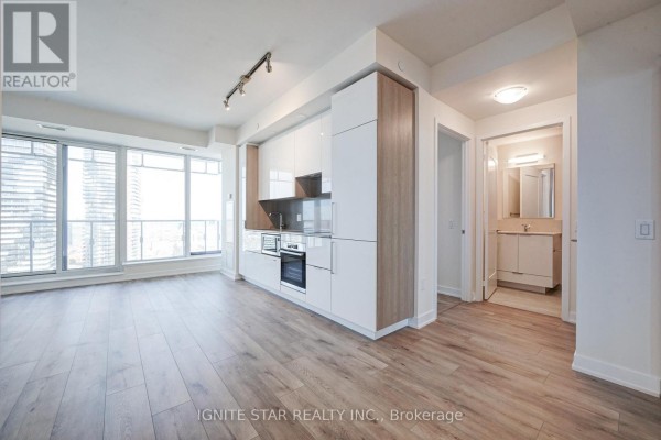 Kitchen area featuring white and wood cabinetry with a view of the living space - 4008 - 28 Freeland Street, Toronto
