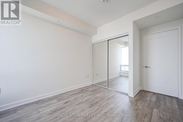 Empty bedroom with mirrored closet doors and large window providing natural light - 4008 - 28 Freeland Street, Toronto