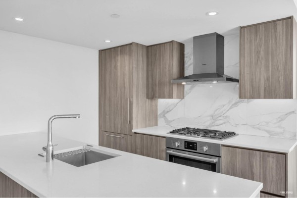 Kitchen with stainless steel appliances, marble backsplash, and wood cabinetry. - 4008 9887 Whalley Boulevard, Surrey