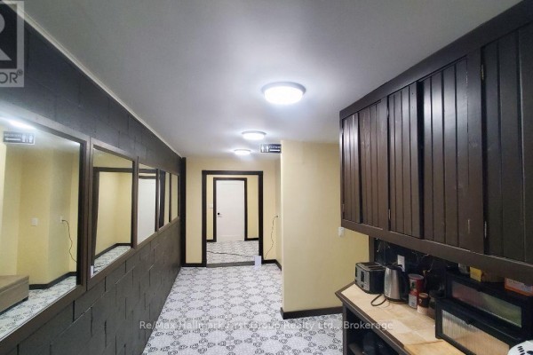 Hallway with mosaic floor tiles, dark wood paneling, and mirrors on the left wall. - 4008 Moneymore Road, Tweed)