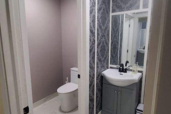 Small bathroom with a grey vanity, white sink, black faucet, and patterned wallpaper. - 4008 Moneymore Road, Tweed)